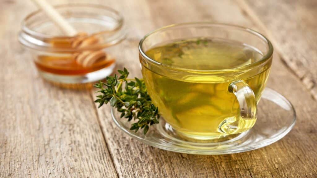 Cup of thyme tea with honey on wooden table