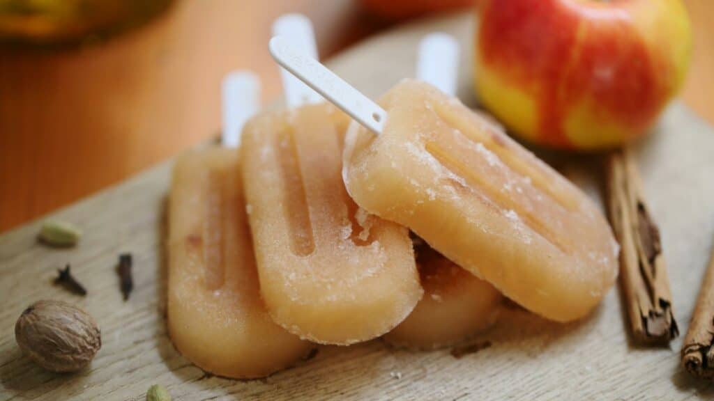 Popsicles au jus de pomme sur planche de bois avec pomme