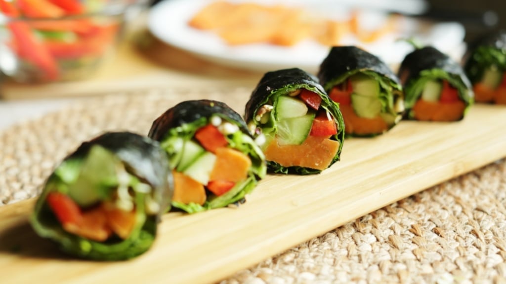 Tavola di legno con involtini di patate dolci nori